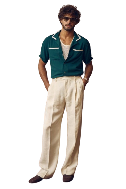 Man in black sweater and beige trousers standing on a tree-lined path.